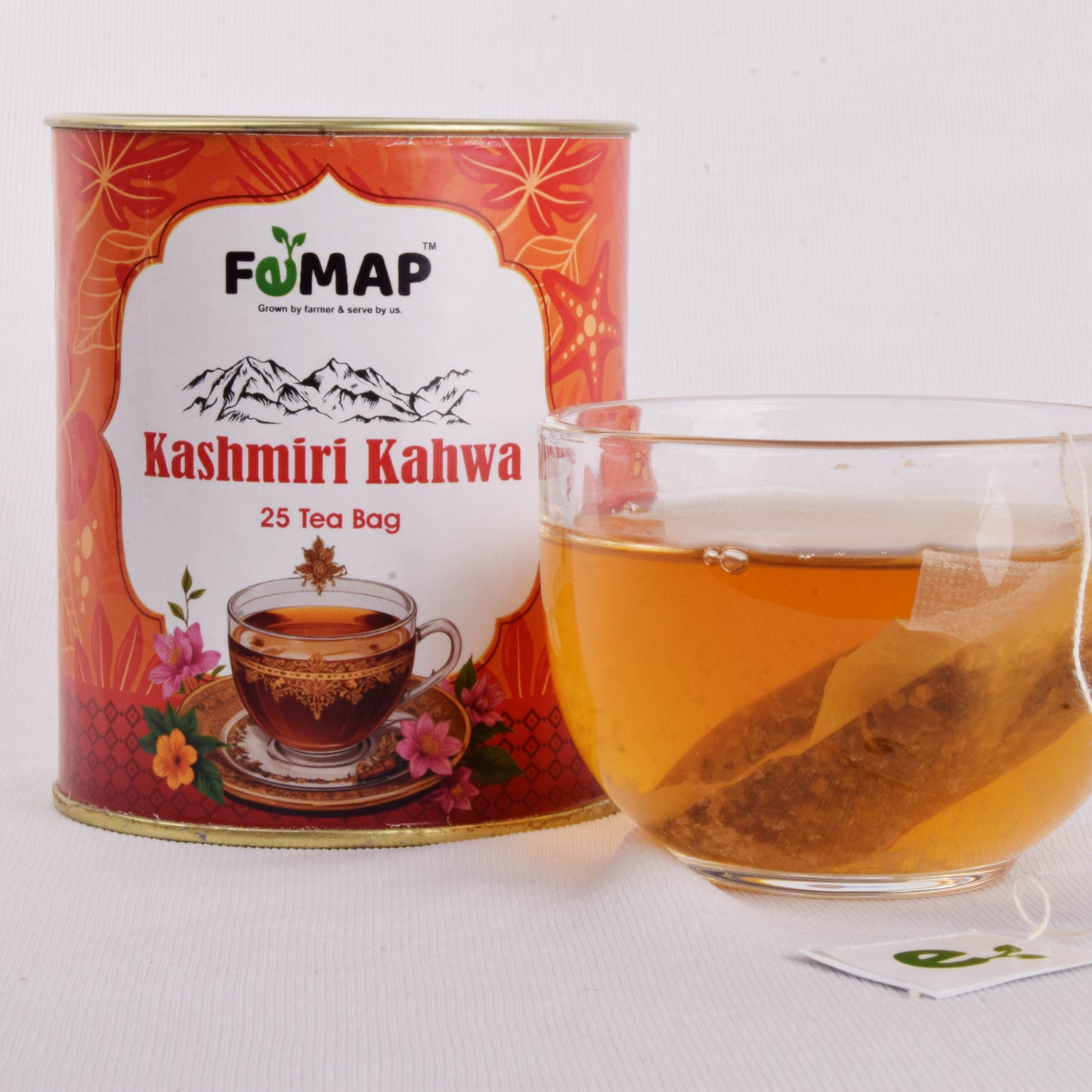 FEMAP Kashmiri Kahwa green tea tin with a clear glass cup of freshly brewed tea and visible tea bag.
