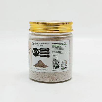 Jar of black salt powder with a gold lid on a white background