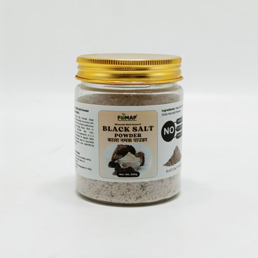Jar of black salt powder with a gold lid on a white background
