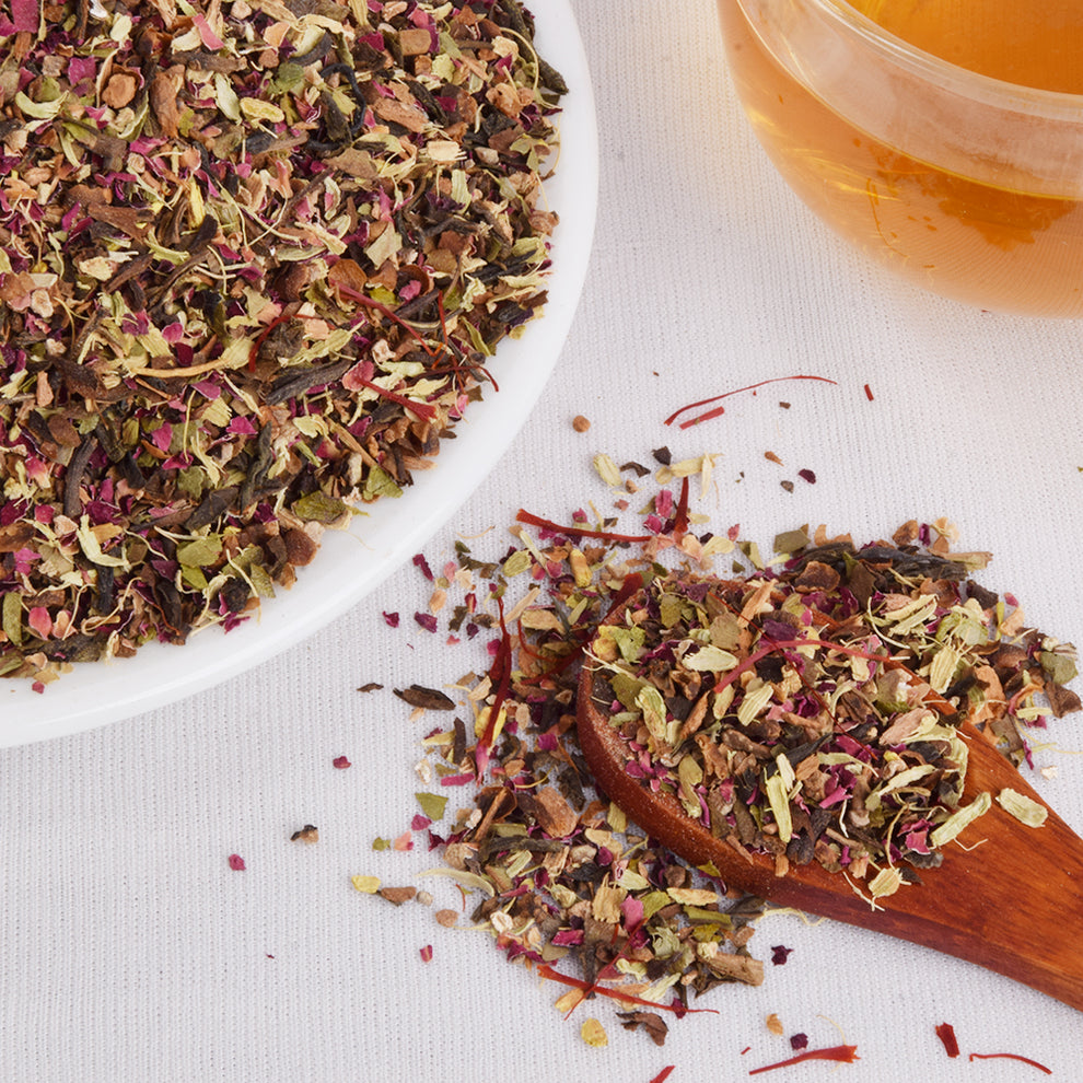 Cup of brewed Kashmiri Kahwa tea with FEMAP packaging – aromatic spiced green tea steeped to golden hue.