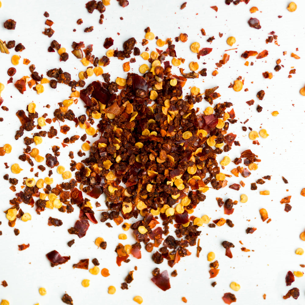 Pure red chilli flakes from FEMAP scattered on white background