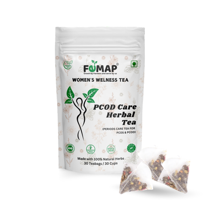 Packaging of FEMAP Women's Wellness Tea, PCOD Care Herbal Tea with two sachets of tea leaves visible in front. The packaging is predominantly white with green tea leaves and text, indicating it is a herbal tea product.